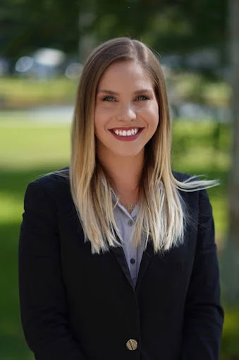 Portrait of Gabrielle Penalta, attorney, smiling outdoors in a professional blazer.